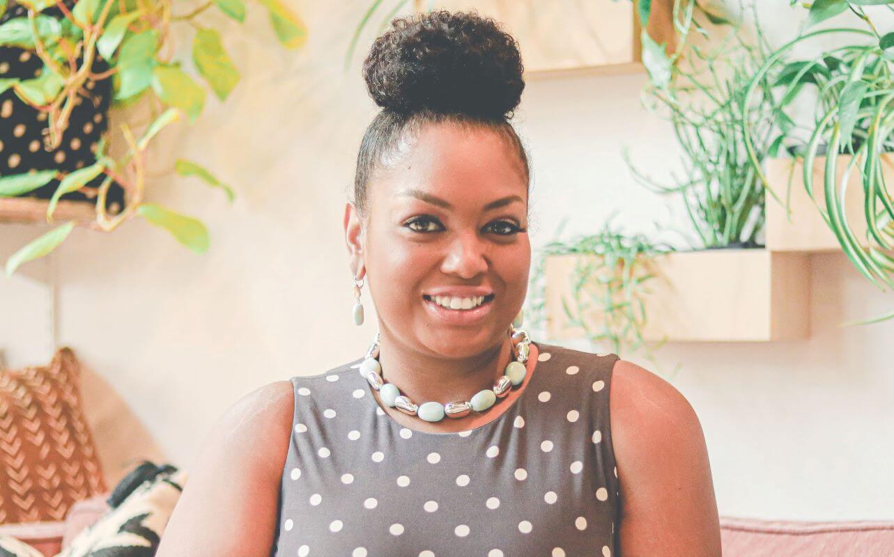 Meet Kionna Comer! An interview with Kionna Comer, REALTOR® at The Lux Life Real Estate Group at Keller Williams Arizona Realty. Kionna serves as the Chairperson of the Diversity, Equity, and Inclusion Committee on the Keller Williams Arizona Realty Agent Leadership Council (ALC) for 2022. Kionna is smiling, facing forward, wearing a gray dress with white polka dots on it, beautiful necklace and earrings, and her dark hair is in a bun on top of her head. Welcome Kionna Comer